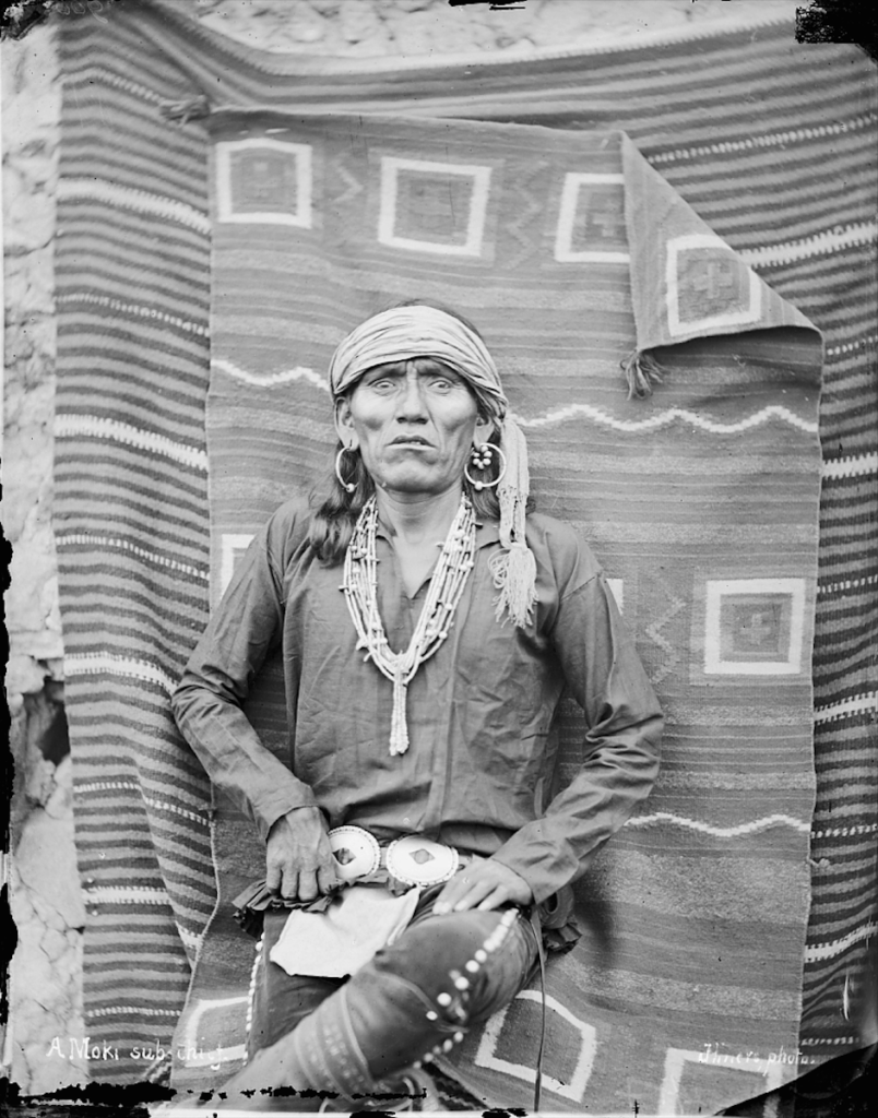 Homme Hopi sous-chef Moki en costume traditionnel avec ceinture et ornements. Hillers-1879