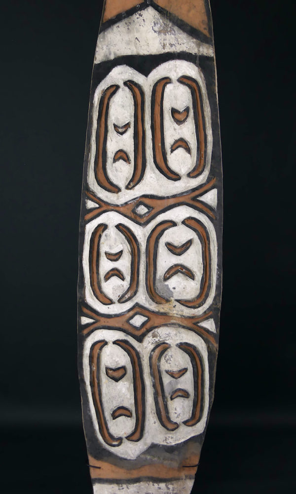 Grand bouclier de guerre Kombai en bois peint sur socle (détail face)