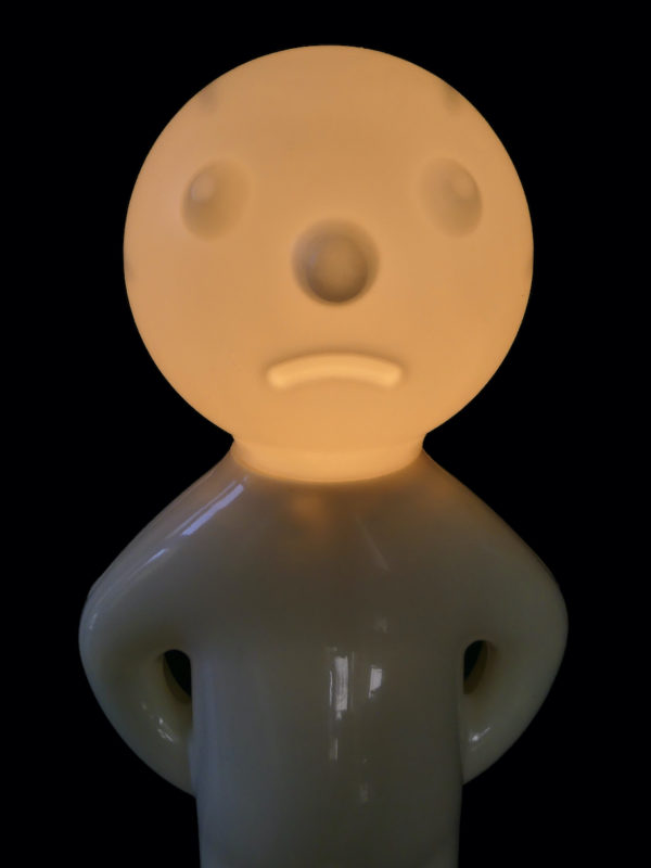 Lampe Mr. P blanche présentée sur socle rond (allumée)