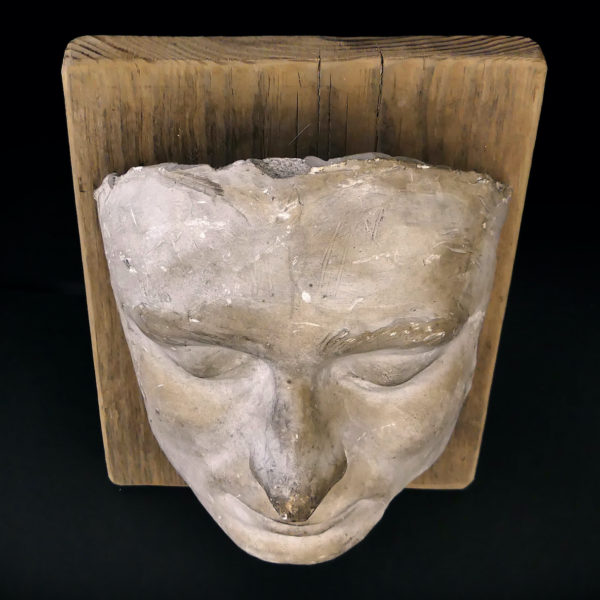 Masque mortuaire ancien en plâtre présenté sur planche de bois brut (dessus)