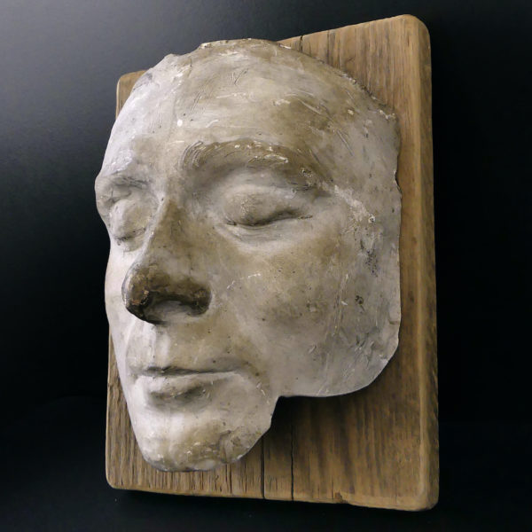 Masque mortuaire ancien en plâtre présenté sur planche de bois brut (3/4)