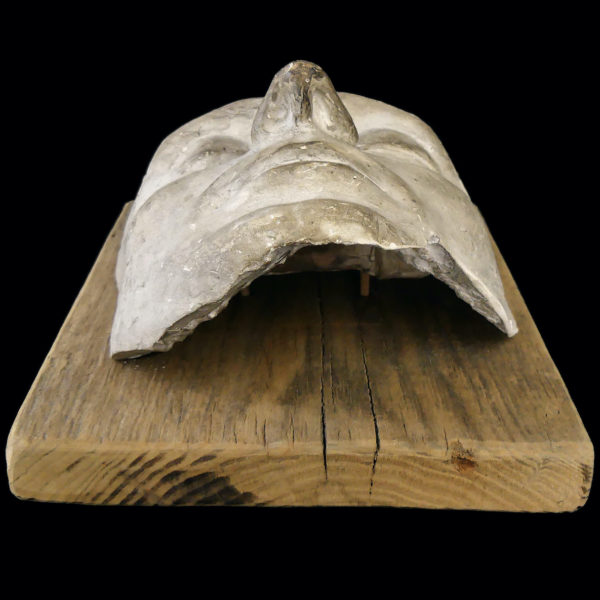 Masque mortuaire ancien en plâtre présenté sur planche de bois brut (dessous)