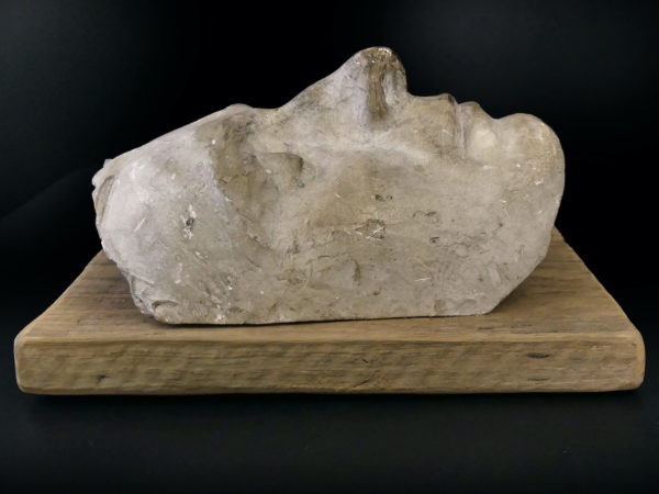 Masque mortuaire ancien en plâtre présenté sur planche de bois brut (profil)